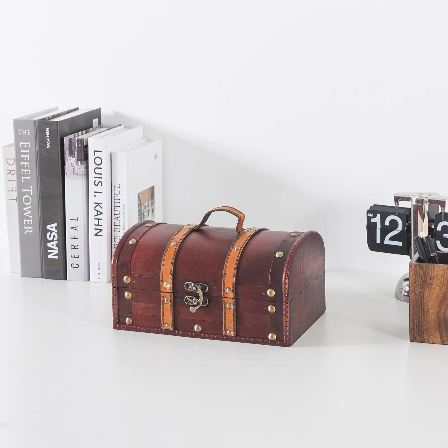 Shows the chest styled on a desk beside books and decor to highlight its vintage look.