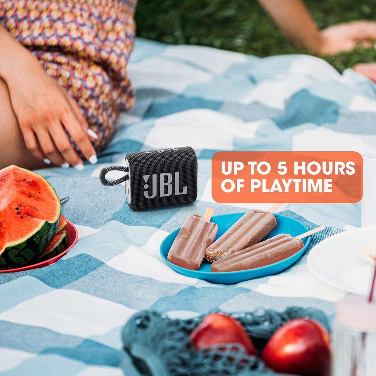Highlights long battery life for extended outdoor use. Reassures shoppers it will last through a full picnic or day out. Shows the speaker in a picnic setting as an outdoor entertainment option.