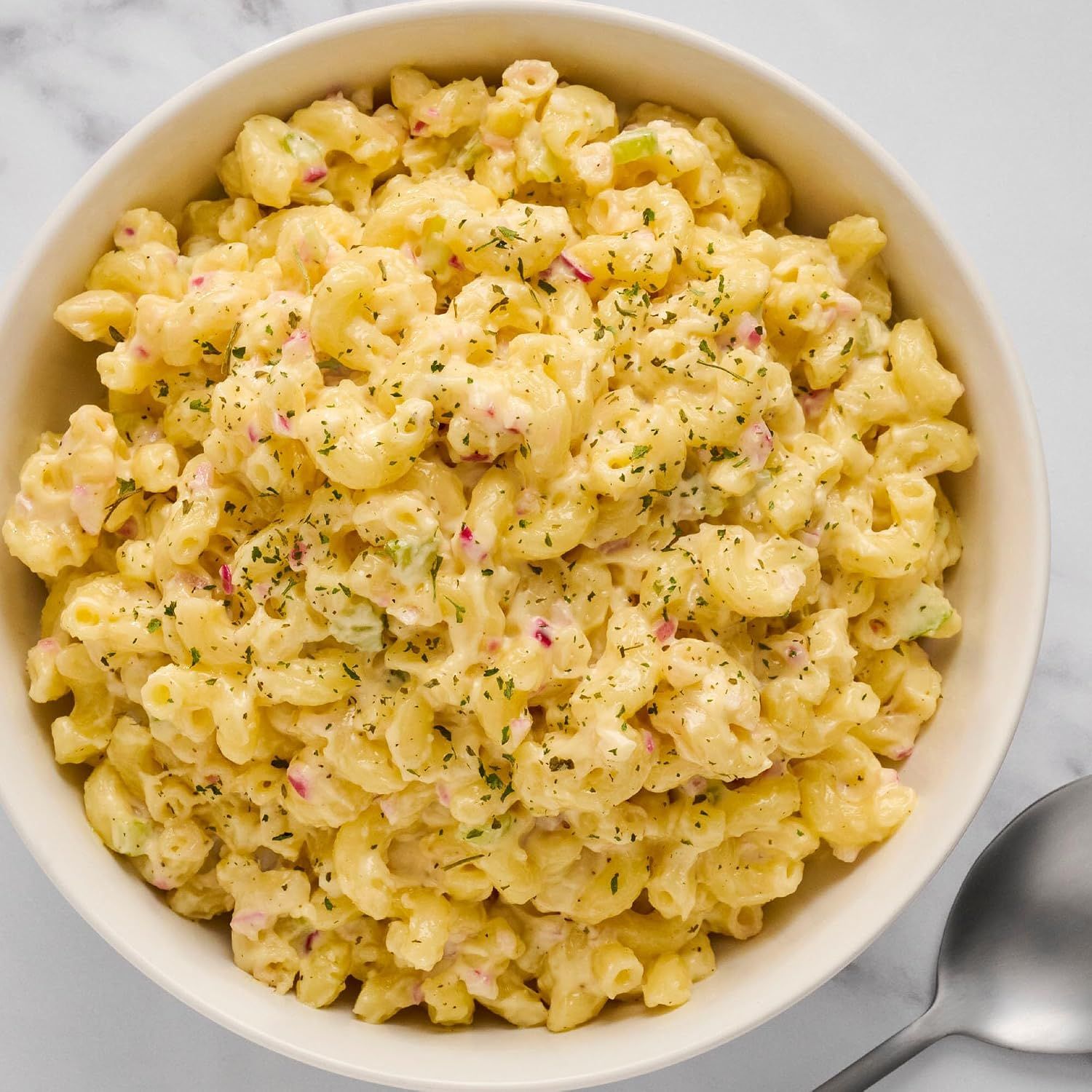 Shows the mustard used in a macaroni salad as a creamy dressing. Shows an appetizing macaroni salad serving with no text overlay.