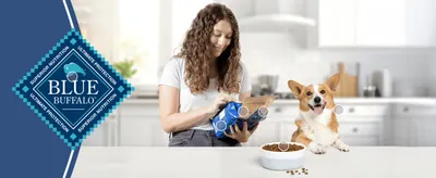 Puts the Blue Buffalo logo and its 'Superior Nutrition, Ultimate Protection' promise up front to build trust in the brand. Shows an owner feeding a happy dog at home so shoppers picture the product…