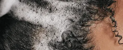 Shows the product lathering on real hair to convey a rich, effective wash experience.