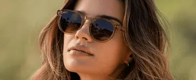 Shows a model wearing the sunglasses outdoors to help shoppers picture themselves using the product.