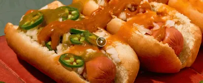 Shows the loaded hot dogs in an appetizing close-up to invite shoppers to play a video demonstrating the sauce in use.