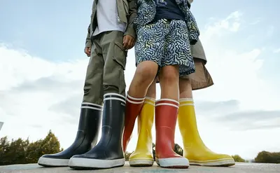 Shows the product (rain boots) in a real-world outdoor setting to help shoppers envision ownership and usage scenarios.