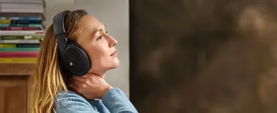 Shows a woman relaxing in a home setting with the headphones on to help shoppers picture everyday comfortable listening.