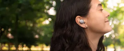 Shows a woman wearing the earbud outdoors so shoppers can picture comfortable all-day wear.
