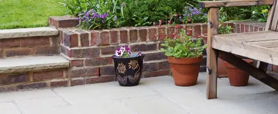 Shows a relaxed garden patio with potted plants and furniture to help shoppers picture the product in an outdoor setting.