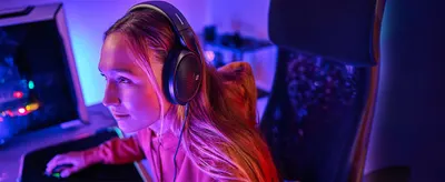 Shows the headphones in a gaming setting to help shoppers see them fitting an immersive desk routine.