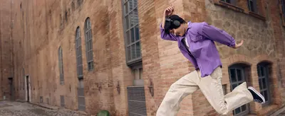 Shows the wireless headphones in an energetic city moment to help shoppers picture them in active daily life.