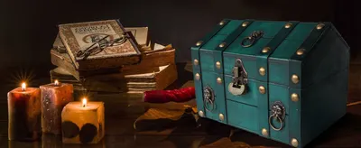 Places the teal treasure chest in a moody vintage setting with candles and old books so shoppers can picture it as a decorative keepsake piece.