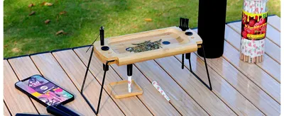 Shows the folding tray in an outdoor camping setting to suggest it works on the go in multiple places. Demonstrates the tray set up on folding legs so shoppers see how simple it is to use anywhere.