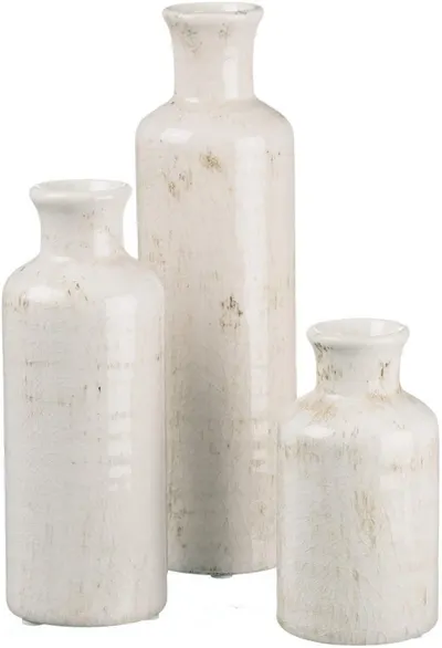 Showcases a set of three white ceramic vases with a distressed finish to highlight their rustic, vintage-inspired design.