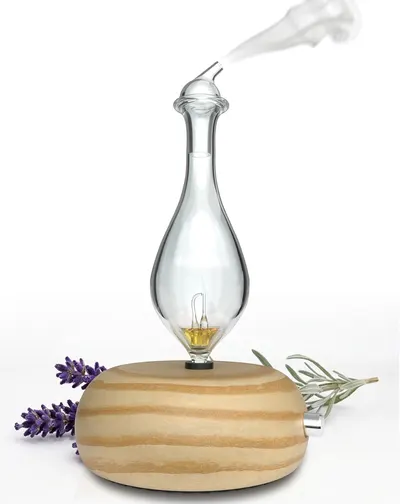 Showcases the product in a styled, real-world context with natural elements like lavender and herbs to communicate its use as an essential oil diffuser and create an appealing, calming aesthetic.