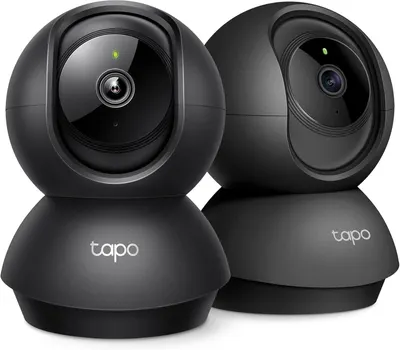 Shows two identical security cameras to communicate that this is a multi-pack purchase, allowing shoppers to see the product design and understand they are buying multiple units. Uses a reflective…