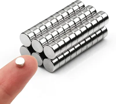 Shows the core product clearly - a set of small cylindrical neodymium magnets arranged in rows, demonstrating the quantity included in the purchase. Uses a human finger holding one magnet to provide…