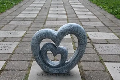 Shows the product in an outdoor memorial or garden setting to help shoppers visualize how the decorative sculpture looks in a real-world environment.