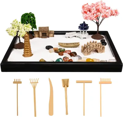 Displays the complete desktop zen garden kit with all included decorative elements (trees, pagoda, bridge, stones, sand, tools) to show shoppers exactly what they will receive and how the product…