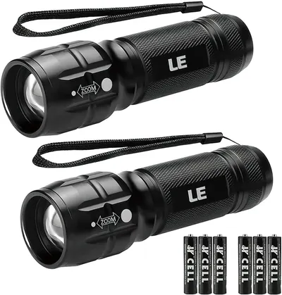 Shows two identical tactical flashlights with zoom functionality and textured grip design to communicate the core product features and that this is a 2-pack offering. Displays the included AAA…