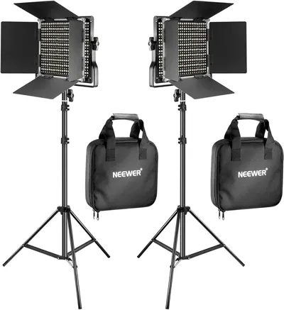 Shows the complete professional lighting kit including two LED panel lights with barn doors, adjustable tripod stands, and branded carrying cases to communicate the full value and portability of the…