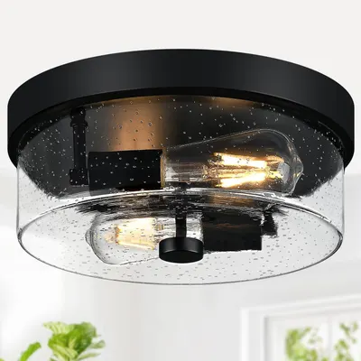 Displays the core product, a flush-mount ceiling light fixture with a seeded glass shade and black finish, to show shoppers exactly what they will receive. Shows the light fixture installed in a…