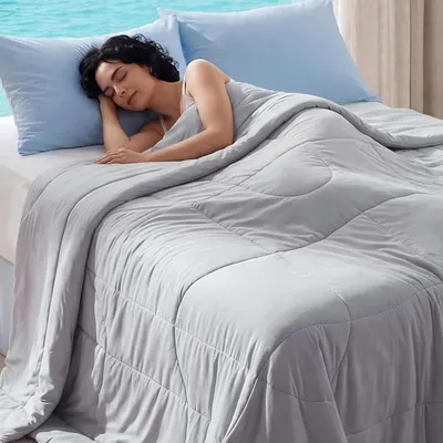 Shows a person peacefully sleeping under the comforter to demonstrate comfort, softness, and the restful sleep experience the product provides. Displays the bedding product in a realistic bedroom…