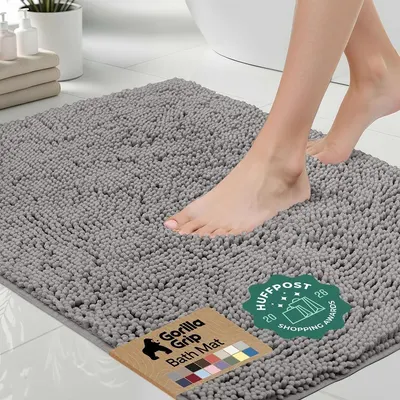 Shows a person standing on the bath mat to demonstrate its size, texture, and real-world use, helping shoppers visualize how it looks and feels underfoot. Displays the bath mat in a realistic…