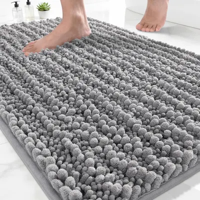 Shows a person standing on the bath mat to demonstrate its real-world use, scale, and plush textured surface, helping shoppers visualize how it looks and feels underfoot. Displays the bath mat in a…