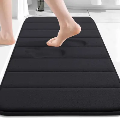 Shows the core product, a black memory foam bath mat with horizontal ribbed texture, displayed in a bathroom setting to help shoppers visualize the product.…