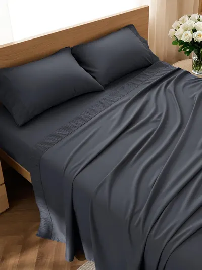 Showcases the complete bedding set including sheets and pillowcases in an elegant dark gray color, communicating quality and a luxurious sleep experience.…