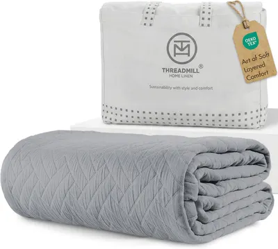 Displays the core product, a gray quilted blanket, clearly showing its texture and quality to help shoppers understand what they are purchasing. Shows the retail packaging and storage bag that comes…