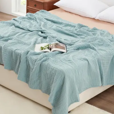 Displays the core product, a soft quilted blanket in a calming blue-green color, to show shoppers its texture, drape, and appearance on a bed. Shows the blanket styled in a realistic bedroom…