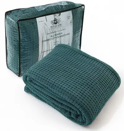 Shows the core product clearly - a teal combed cotton bedcover with textured waffle weave - both folded and in its retail packaging to help shoppers understand what they will receive. Displays the…