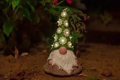 Showcases the product in a natural garden setting to demonstrate its decorative appeal and lighting feature. Highlights the unique illuminated floral hat…