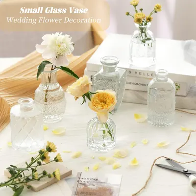 Showcases how the small glass vases can be used to create an elegant and romantic wedding table setting. Demonstrates various ways to use small glass vases for floral arrangements in wedding decor.