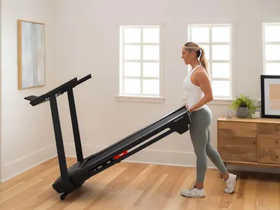 Shows the treadmill being easily stored in a home setting, emphasizing its compact and convenient design for at-home fitness. Demonstrates how the treadmill can be used in a small living space,…