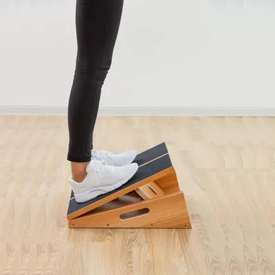 Demonstrates how to use the product for stretching calf muscles, showing proper foot placement and angle.