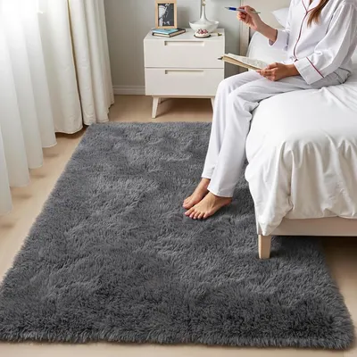 Showcases the plush, comfortable texture of the rug in a real bedroom setting to emphasize its cozy feel and aesthetic appeal. Highlights the rug's soft, plush texture by showing a person's bare…