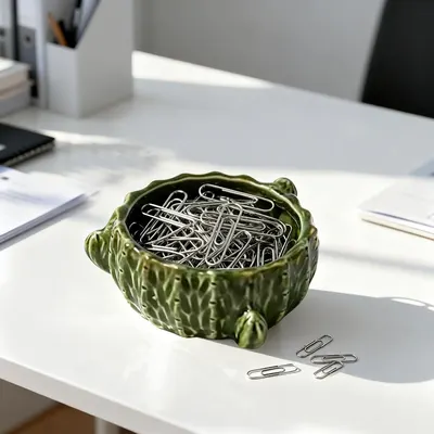 Shows how the decorative bowl can be used to organize and store small office supplies like paper clips, enhancing desk organization and aesthetics.