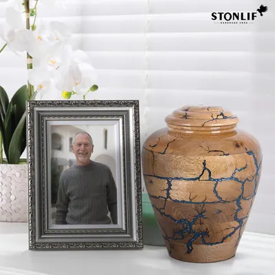 Showcases the handcrafted urn product alongside a framed photo to demonstrate its use as a memorial keepsake.