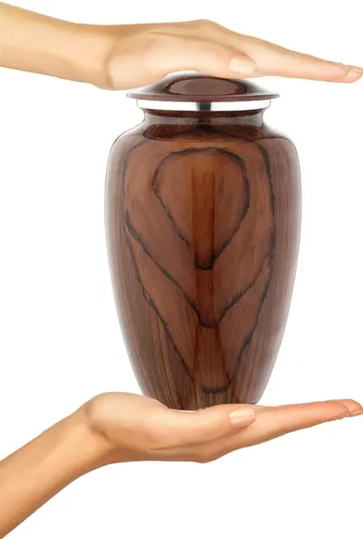 Demonstrates the small, manageable size of the urn by showing it held between two hands.