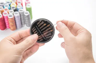 Shows the variety of needles included in the sewing kit, demonstrating the product's versatility for different sewing needs. Demonstrates how to use the product by showing hands threading a needle,…