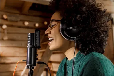 Shows the product being used in a real-world recording studio environment to help shoppers visualize how the microphone and headphones work together during vocal recording sessions.
