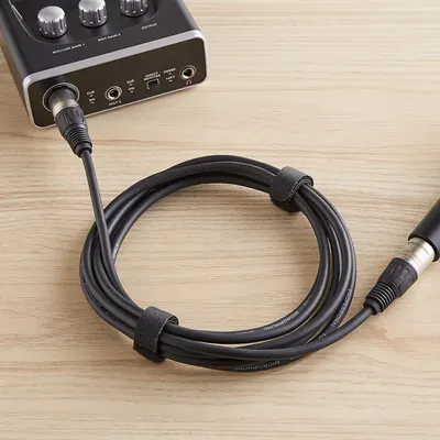 Shows the microphone cable connected to an audio interface in a real-world setting to help shoppers visualize how the product is used and what it looks like when set up.
