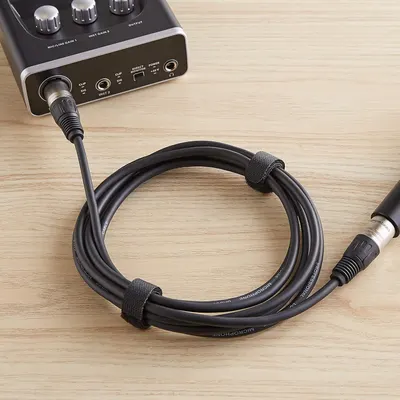 Demonstrates the cable's built-in velcro straps that keep the microphone cable organized and tangle-free during storage or transport.