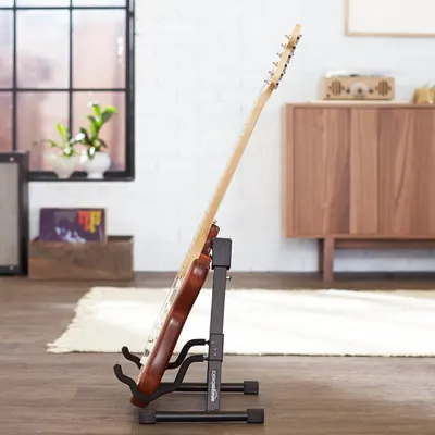 Shows the guitar stand holding a guitar in a real-world home setting to help shoppers visualize how the product looks and functions in their own space.