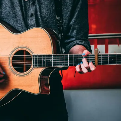 Shows the guitar being played in a natural, real-world setting to help shoppers visualize themselves using the product and connect emotionally with it.