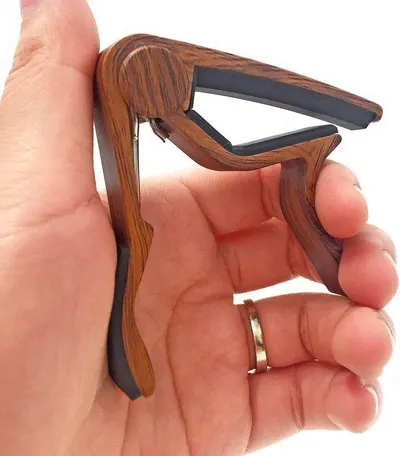 Showcases the high-quality wood grain finish and craftsmanship of the guitar capo to communicate premium materials and aesthetic appeal.