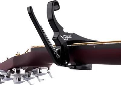 Shows the product attached to a guitar in a real-world context to help shoppers visualize how the capo looks and functions on an actual instrument.