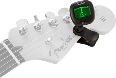 Shows the Fender guitar tuner clipped onto a guitar headstock in a real-world usage scenario to help shoppers visualize how the product attaches and functions.