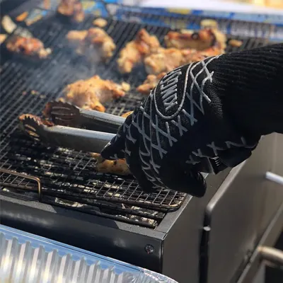 Demonstrates the product's heat-resistant capability by showing it safely handling hot grilling tools over an active grill, reassuring shoppers it provides protection during high-heat cooking.
